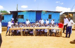 Group photo of students seated at desks with Mini Group employees during education support initiative at SIFA Primary School"